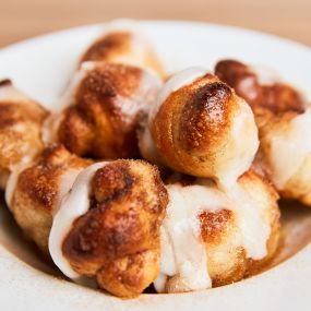 CINNAMON KNOTS (WITH ICING) - Our homemade dough knots with butter and sprinkled sugar and cinnamon. Topped with icing.