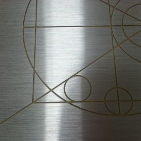 Horizontal Brushed Finish on an aluminum panel that had an etched design on the face along with a fully painted surface.