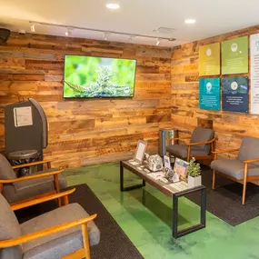 Cozy waiting area with rustic wooden walls, a TV displaying a cannabis image, and comfortable seating.