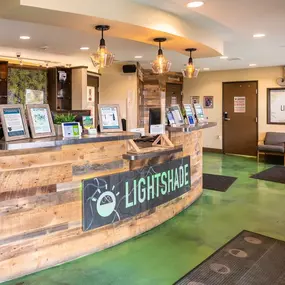 Lightshade reception desk with wood paneling, pendant lighting, and informational displays.