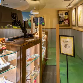 Checkout counter with glass display cases featuring cannabis-related items and a medical patients-only sign.