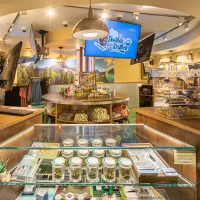 Retail display with cannabis jars, branded merchandise, and digital promotional screens.