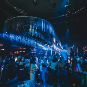 energetic scene with neon lights illuminating the crowd from a dazzling chandelier.