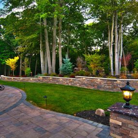 Patio Pavers, retaining wall, columns, and landscaping, finished off with low lighting.