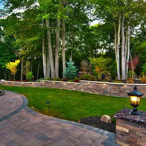 Patio Pavers, retaining wall, columns, and landscaping, finished off with low lighting.