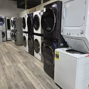 A diverse lineup of front-load and stacked laundry appliances including commercial-style and apartment-friendly washer-dryer combos. Brands like Speed Queen, GE, and Electrolux are featured in this display, showcasing efficient and space-saving laundry solutions.