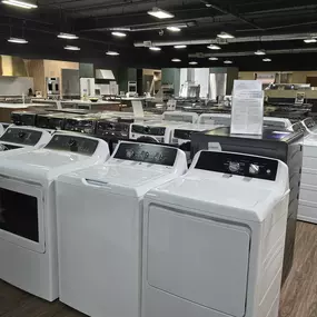 A broad showroom floor lineup of top-load washers and front-load dryers from trusted brands like GE and Speed Queen. This display showcases multiple models side by side, highlighting performance, design variety, and availability for in-store comparison.