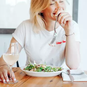 Woman eating a salad with a  glass of wine at Bar 'Cino