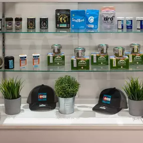 A display shelf at Lightshade Evans Dispensary filled with cannabis products, branded merchandise, and small potted plants.