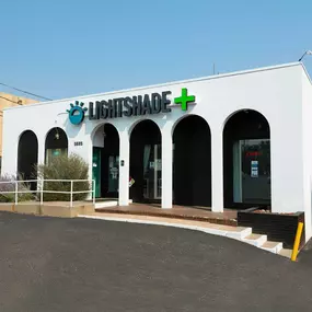 The exterior of Lightshade Evans Dispensary, a white building with arched entryways and the Lightshade logo above the entrance.