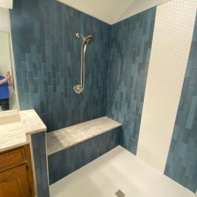 Walk-in shower using variant blue subway tile. Tile used on shower floor serves as design accent.