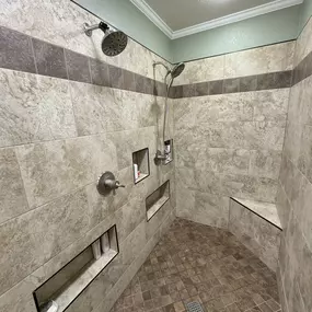 Large walk-in tile shower with accent band, low niche product area for easy access. We also included a corner bench and dual shower heads.