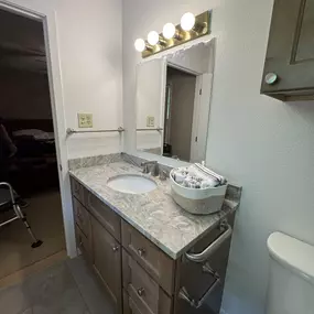 New vanity with granite counterop and grab bar on the side.