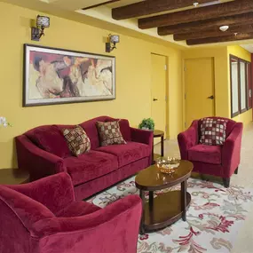 Living room with yellow walls and red furniture at The Verandas in Canoga Park