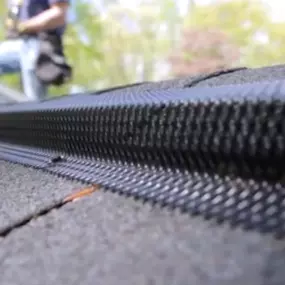 Securing a ridge vent at the peak of the roof to stop squirrels from entering.