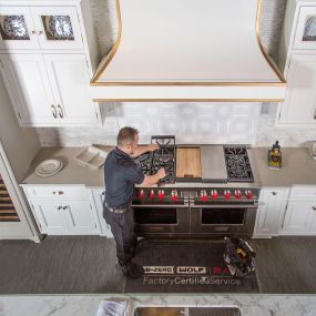 A technician repairs a Wolf range.