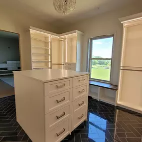 Step into a world of style and organization ✨ This custom walk-in closet is a dream come true! White elegance meets sleek black flooring, with glass-inset doors, integrated lighting, drawers with dividers, and integrated ironing board to showcase, care for, and protect your treasures. Every accessor