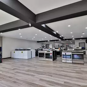 Spacious corner view of the appliance showroom featuring a blend of freestanding ranges, washers, and branded sections like GE Profile.