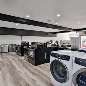 Closer look at the rear side of the showroom, featuring a wide selection of freestanding ranges and dishwashers along the wall.