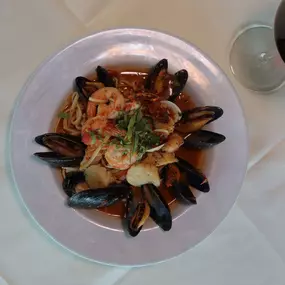 Nino's Authentic Italian Cuisine Zuppe Di Pesce Dish with shrimp, scallops, clams, mussels, and grouper in a white wine tomato sauce.