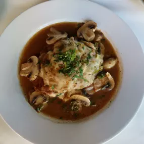 Nino's Authentic Italian Cuisine Vitello Alla Romano Dish with scallopini veal, layers of eggplant, prosciutto, scallions, finished in a white wine mushroom sauce.