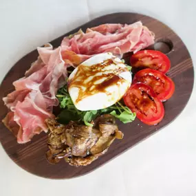 Nino's Authentic Italian Cuisine Burrata Antipasti with creamy Italian mozzarella served with prosciutto roasted vegetables and arugula.