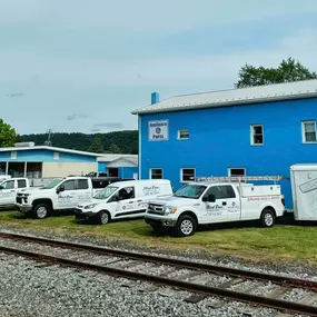 Front view of Flick Brothers Electric in Bloomsburg, PA, showing their bright blue building, branded service vehicles, and signage.
