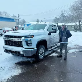 Two employees standing near a Flick Brothers Electric truck in the snow.