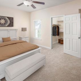 Vista style bedroom with built in desk walk in closet ceiling fan and carpet