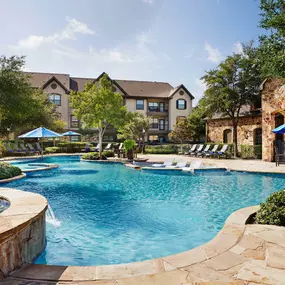 Resort style pool with water feature lounge seating and outdoor dining