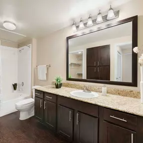 Vista style bathroom with granite countertops bathtubs with curved shower rods and espresso cabinets