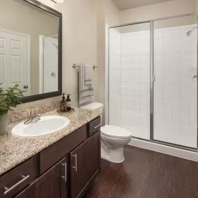 First-floor bathroom with walk-in shower and wood-style floor at Camden Riverwalk apartments in Grapevine, TX