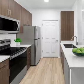 Camden San Marcos Apartments Scottsdale AZ spacious kitchen with woodlike flooring, stainless steel appliances, white quartz countertops, designer lighting, and brushed nickel fixtures