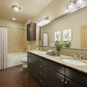 Bathroom with double vanity and bathtub with tile surround at Camden La Frontera apartments in Round Rock, TX