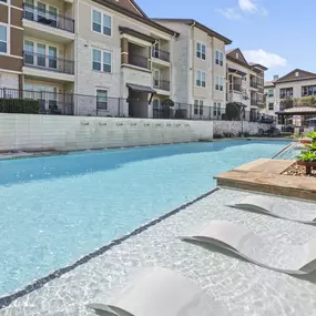 Resort-style pool with waterfall and tanning ledge at Camden La Frontera apartments in Round Rock, TX