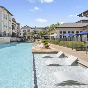 Resort-style pool with in-water loungers at Camden La Frontera apartments in Round Rock, TX