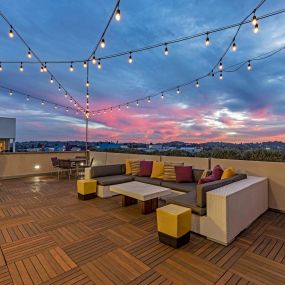 Skydeck lounge with seating areas and string lights at dusk overlooking los angeles