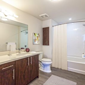 Large bathroom with quartz countertops linen cupboards and bathtub with curved shower rod