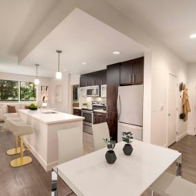 Open concept dining room near luxury kitchen with white quartz countertops, stainless steel appliances, and room for barstool seating