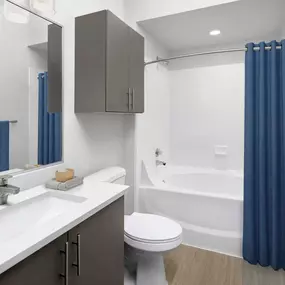 Bathroom with white quartz countertop, dark gray cabinets and a soaking tub with extended shower rod