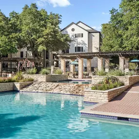 Resort-style pool with waterfall and cabana seating at Camden Huntingdon apartments in Austin, TX