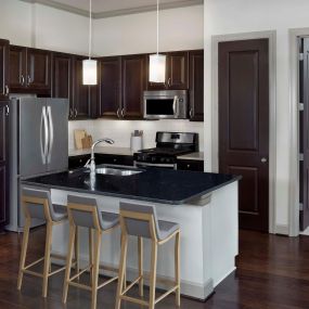 Tower kitchen with black quartz countertops, hardwood-style flooring, and pendant lights
