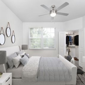 Spacious bedroom with walk-in closet and lighted ceiling fan at Camden Westchase Park apartments in Tampa, Florida.