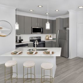 Open kitchen with stainless steel appliances and kitchen island in the Bennington floor plan at Camden Westchase Park apartments in Tampa, Florida.