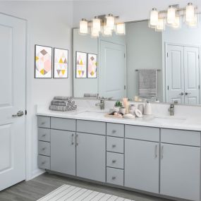 Beautifully renovated bathroom featuring modern flat panel gray cabinetry with satin nickel finish hardware and fixtures, quartz countertops, and LED vanity lighting.