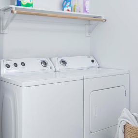 Renovated laundry room with wood shelving and rods.