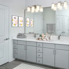 Beautifully renovated bathroom featuring modern flat panel gray cabinetry with satin nickel finish hardware and fixtures, quartz countertops, and LED vanity lighting.