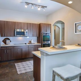 Kitchen with bar seating glass cooktop subway tile backsplash and track lighting