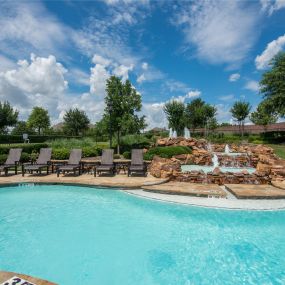 Resort-style pool with poolside deck chairs and fountains at Camden Panther Creek in Frisco, TX