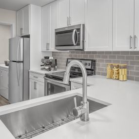 Kitchen with white quartz countertops and white cabinetry with adjacent laundry room